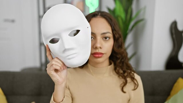 A thoughtful woman holding a white mask in a cozy living room interior