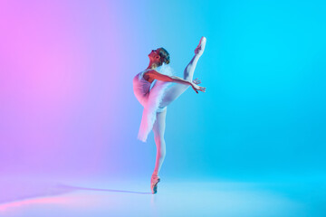 Tenderness and grace. Portrait of young flexible ballerina dancing in neon light against vivid...