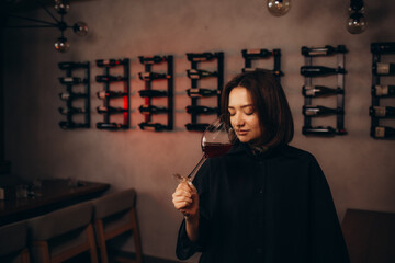 Young female sommelier tasting sorts of wine in cellar