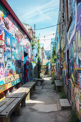 Fototapeta premium A quirky street art alley adorned with vibrant murals, graffiti tags, and urban artworks, showcasing the creativity and expression of local artists in a colorful and dynamic outdoor gallery. 