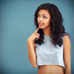 Fototapeta premium Fashion, space and thinking with trendy woman in studio isolated on blue background for casual style. Future, idea and vision with cool or confident model on mockup in stylish clothing for chic