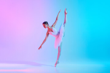 Fototapeta premium Art through motion. Young ballerina in white tutu doing arabesque in motion in neon light against vivid gradient background. Concept of art, movement, classical and modern fusion, beauty and fashion.