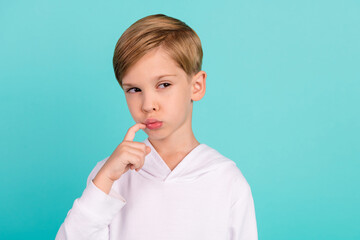 Photo of clever minded boy touching chin look copyspace guessing isolated on cyan color background