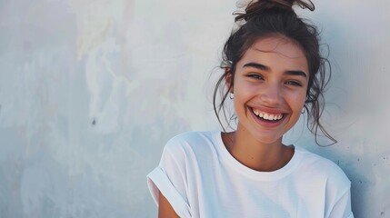 Fototapeta premium portrait dune jeune femme souriante en tshirt blanc et jean devant un mur blanc photo lifestyle