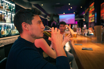 Man drinking beer at bar with their friends