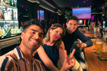 Group of friends taking a selfie at a bar in the evening