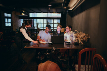 Group of friends collaborating in a cozy cafe during the evening
