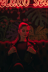 Young woman in a dark lounge under red neon light at night