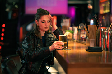 Woman in leather jacket enjoying evening drink at a cozy bar