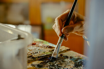 Woman's hand carrying paint brush on canvas