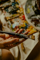Woman's hand carrying paint brush on canvas