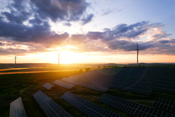 Solar panels park and wind turbines at sunset.Windmill turbines generating green energy...