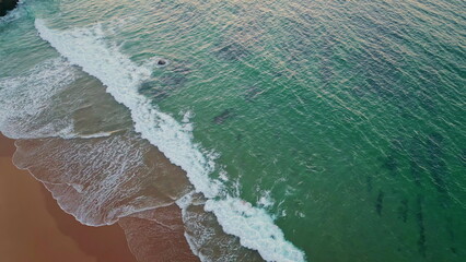 Drone ocean waves washing coastline. Peaceful scenic landscape on golden sunset