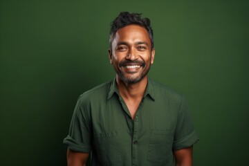 Fototapeta premium Portrait of a content indian man in his 30s smiling at the camera isolated in soft green background