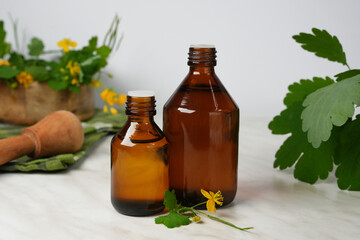 Medicinal herb celandine in a basket, celandine infusion, healing oil in small glass bottles. Side view.