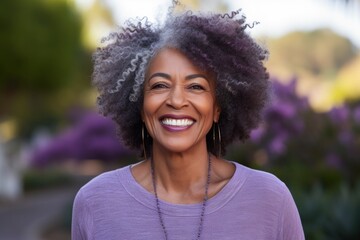 Portrait of a grinning afro-american woman in her 50s smiling at the camera over soft purple...