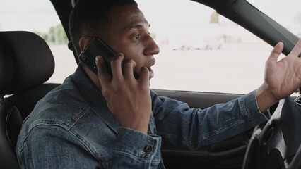 Dissatisfied young man talking on the smartphone, driving his car. Slow motion