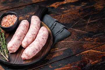 Fresh Raw Bratwurst meat sausages ready for cooking on wooden board. Wooden background. Top view....