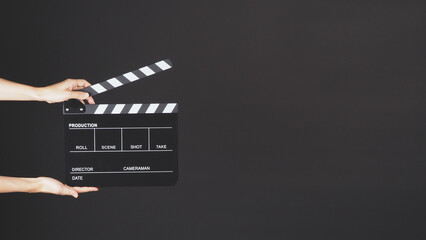 Hands holding Clapper board on black background.