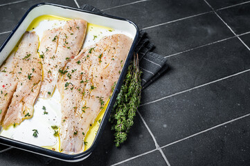 Marinated ocean red perch fillet with olive oil, thyme and spices. Black background. Top view. Copy...