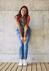 Fashion, smile and portrait of woman by wall with casual, trendy and dungaree outfit with sneakers....