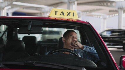 Young taxi driver sitting in the and drinking coffee.