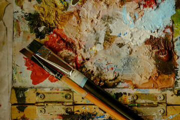 Used brushes on an artist's palette of colorful oil paint