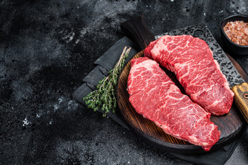 Marbled beef Denver raw meat steak with herbs. Black background. Top view. Copy space