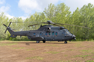 Black painted modern H225M military transport helicopter stationary on the ground