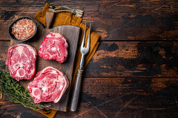 Fresh Raw lamb neck meat with bone on a wooden board with herbs. Wooden background. Top view. Copy...
