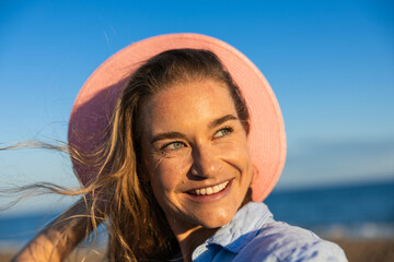 Radiant smiling woman in summer hat at the beach