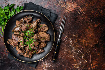 Fried chicken liver with onions and parsley in a plate. Dark background. Top view. Copy space