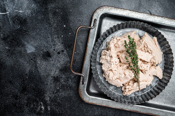 Canned Cod liver with thyme in oil on plate. Black background. Top view. Copy space