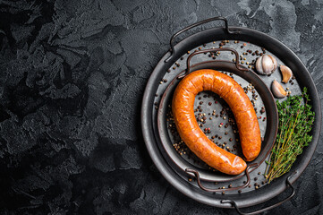 Smoked sausage with thyme and spices in a steel tray. Black background. Top view. COpy space