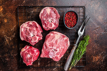 Fresh Raw lamb neck meat slices, mutton meat on a rack with herbs. Dark background. Top view