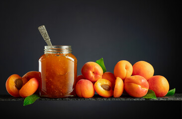 Apricot jam in glass jar and fresh fruits.