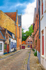 Bruges cityscape with empty narrow street, paving stone road, colorful buildings and houses with brick walls, Brugge city historical center old town medieval district, West Flanders province, Belgium