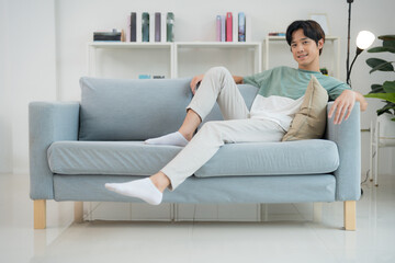 Young man relaxing comfortably on a modern sofa at home