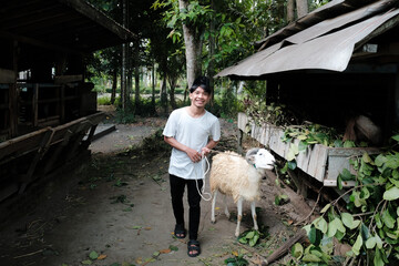 happy man carrying a goat on the farm. eid al adha concept