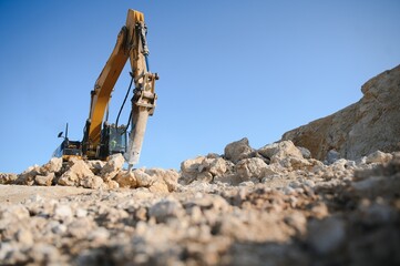 Hydraulic breaker hammer in a quarry for limestone mining with an excavator
