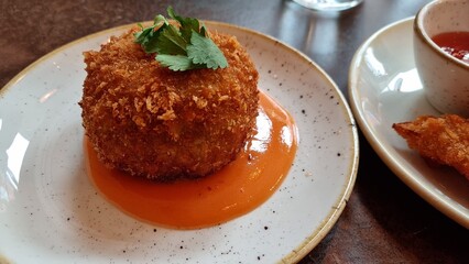 Vegetarian jalapeno ball on plate in resturant with fresh green and sauce