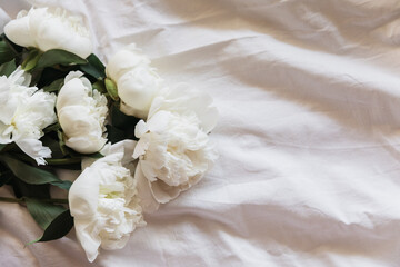 White peonies on cotton fabric background. A serene display of white peony flowers resting on a...