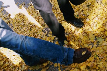 Two feet kicking a ginkgo ,close up of a hand holding a drill