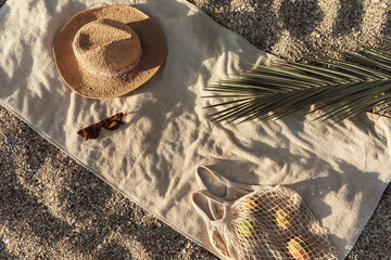 Straw hat, sunglasses, towel, bag on beach sand background. Aesthetic lifestyle, summer vacation...