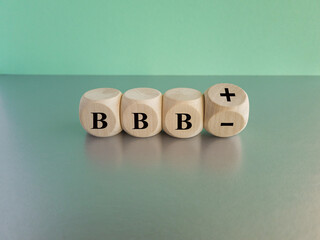 Turned a wooden cube and changes the expression BBB minus to BBB plus. Beautiful blue background,...