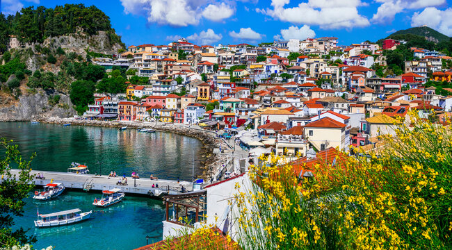 Mediterranean aesthetics in Parga town close up view through yellow flowers colorful houses on peninsula turquoise sea water Epirus Greece summer travel destination wide angle