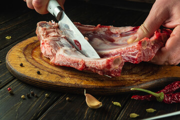 Slicing meat ribs with a knife in the hand of a butcher before preparing a barbecue. Concept of...