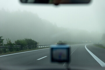 Blick durch die Windschutzscheibe eines Autos auf die Straße einer Autobahn bei Nebelwetter