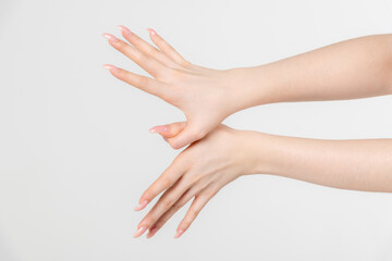 Close-up side view of elegant female hands touching each other during dance against grey...