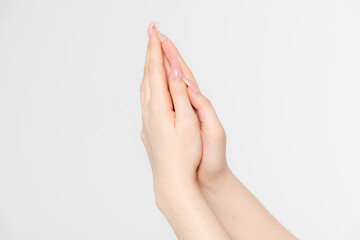 Close-up side view of elegant female hands holding each other in praying gesture against grey...